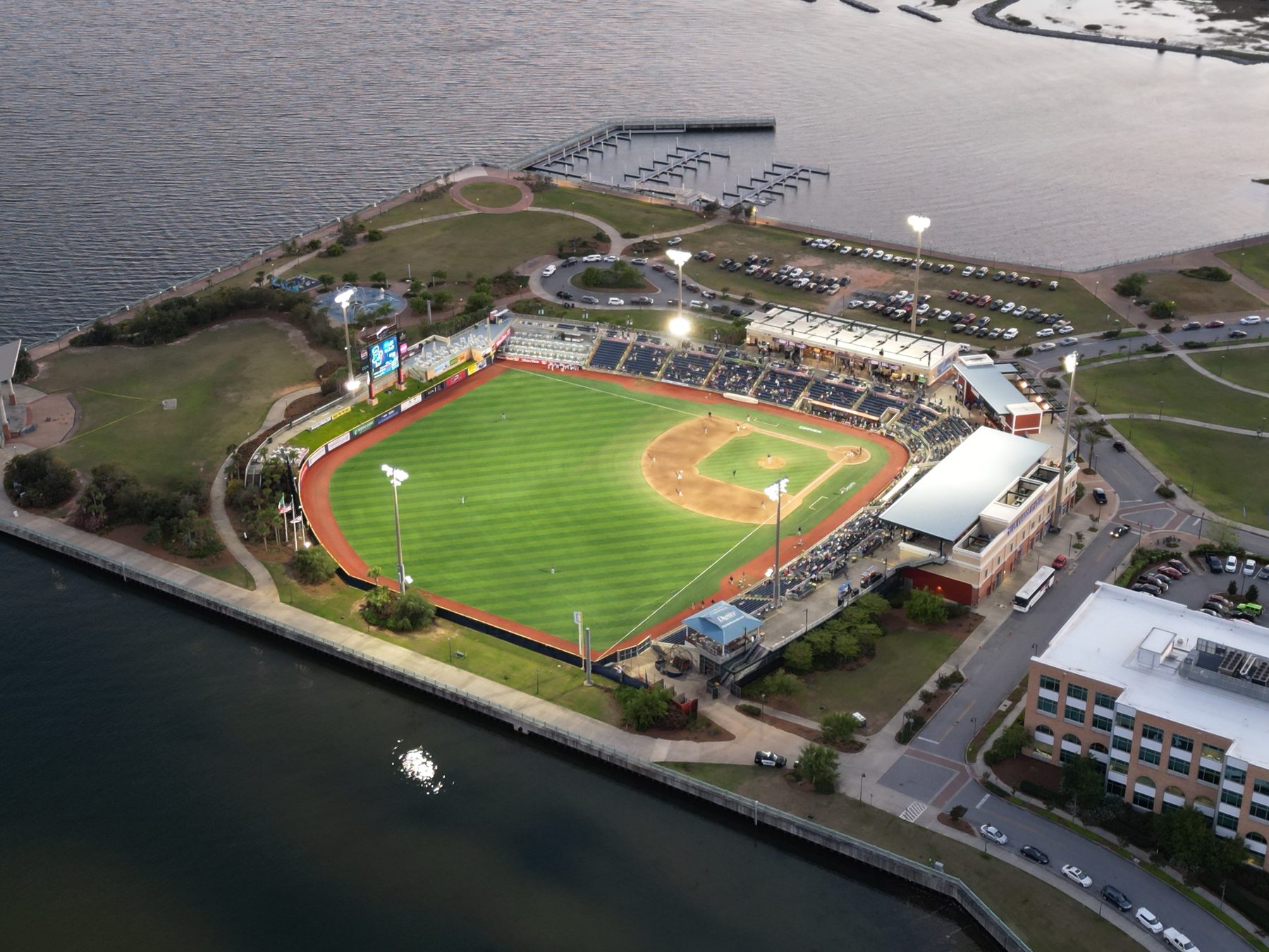 Aerial view of Pensacola's bayfront baseball stadium glowing under evening lights
