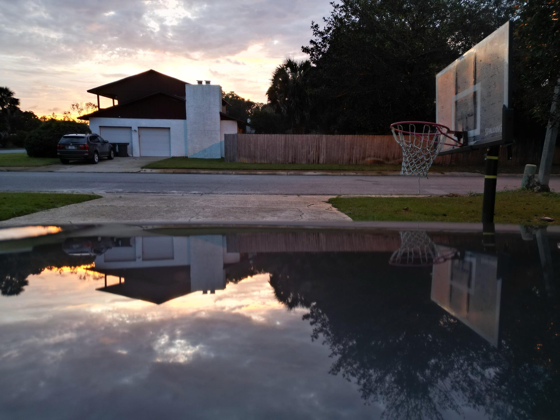 Backyard basketball goal mirrored in a rain puddle after a Gulf Coast storm