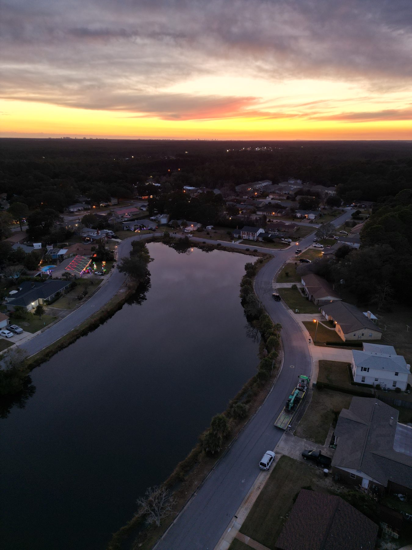 Dusk aerial over a quiet Pensacola neighborhood canal reflecting the sunset sky