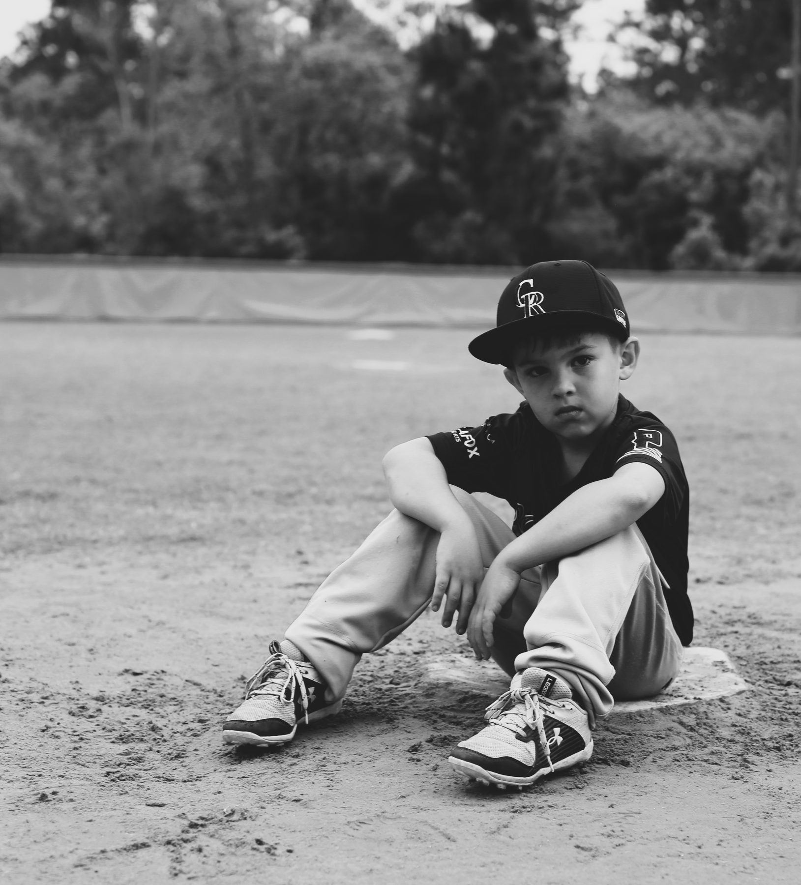 Black-and-white portrait of a young ballplayer sitting on the infield dirt