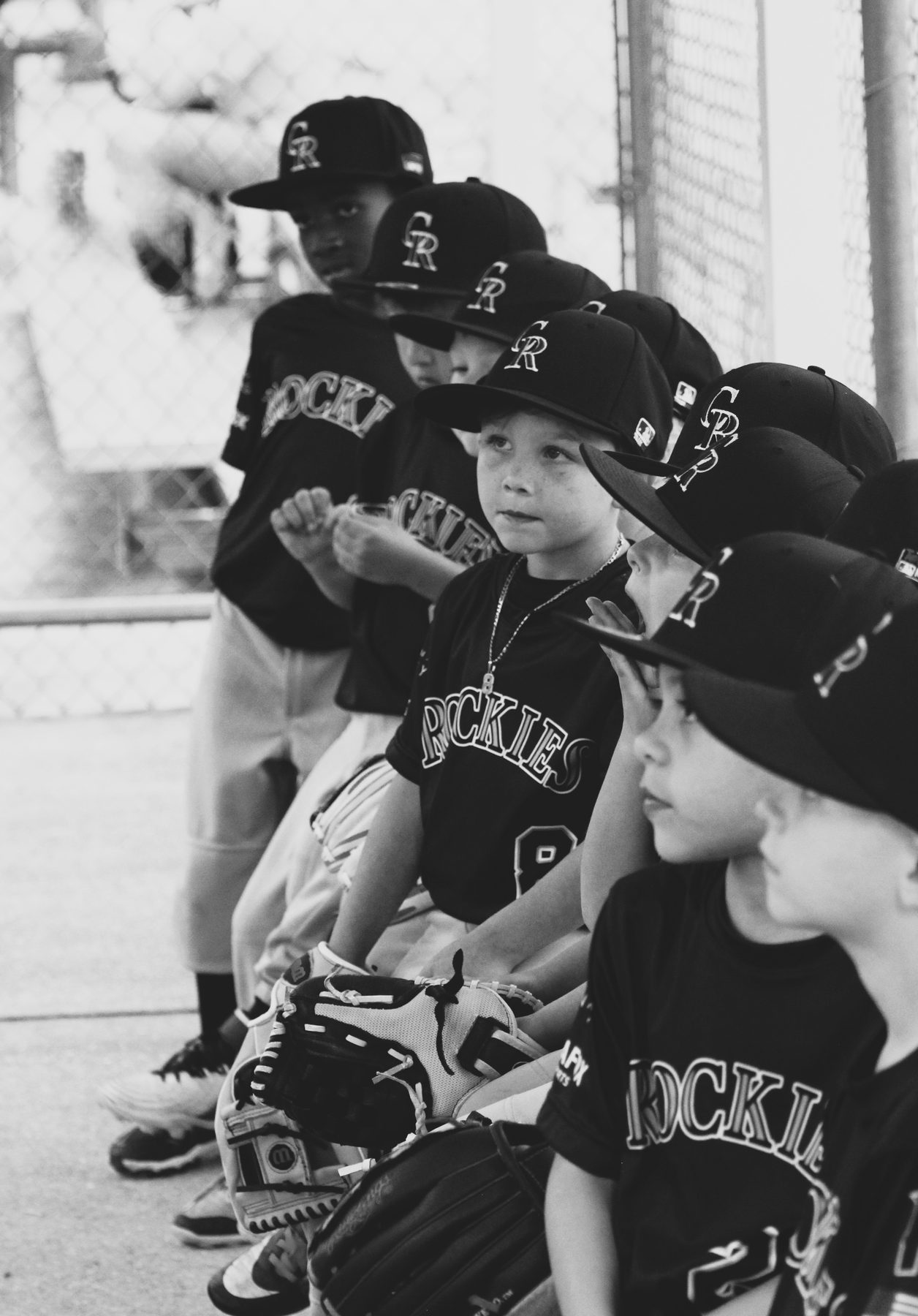 Little league team lined up in caps and jerseys along the dugout fence
