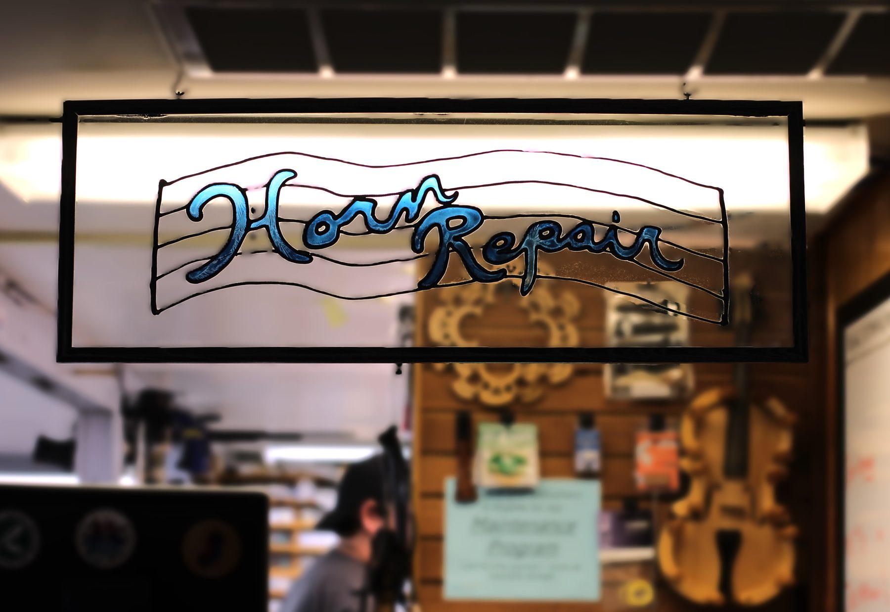 Hand-lettered Horn Repair sign hanging in a music shop