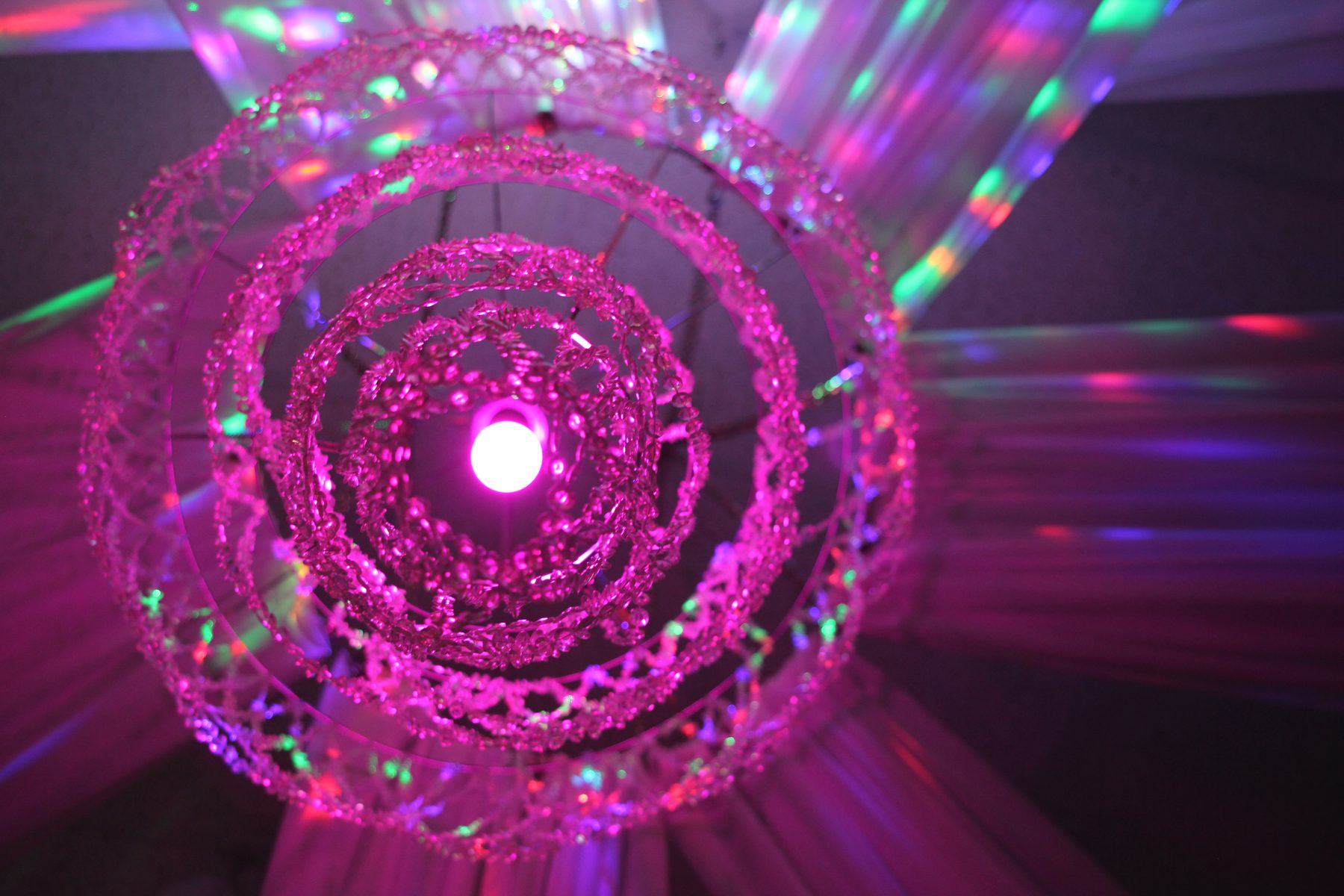 Pink spiral chandelier scattering prismatic light across the ceiling