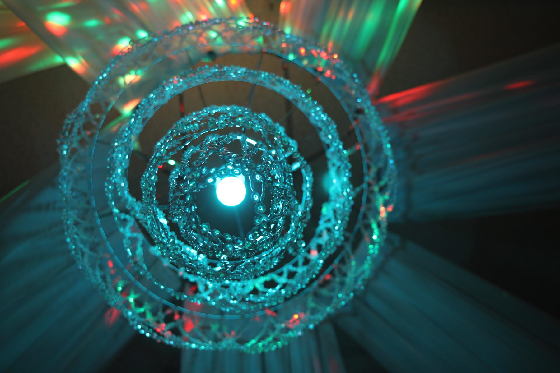 Teal crystal chandelier light art radiating beams of color