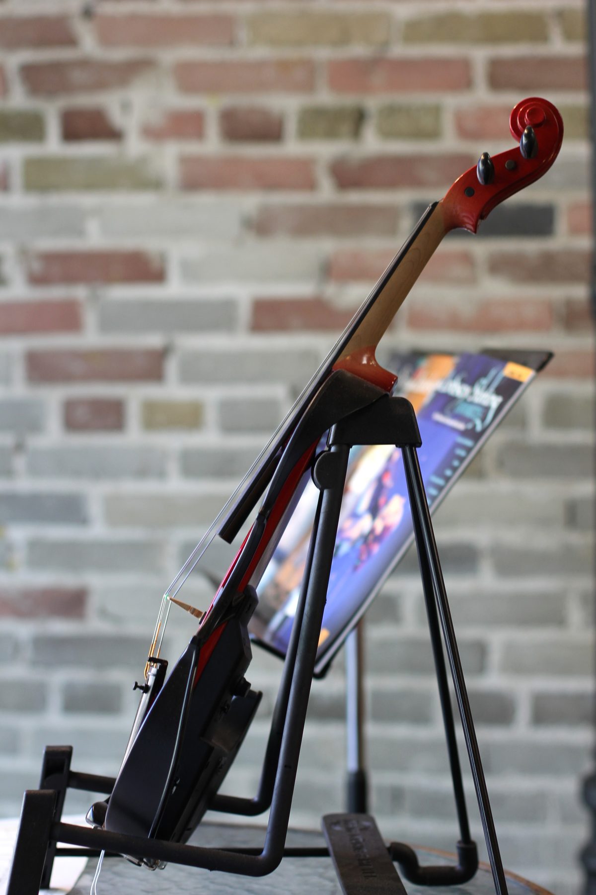 Violin and digital sheet-music stand photographed against a brick wall