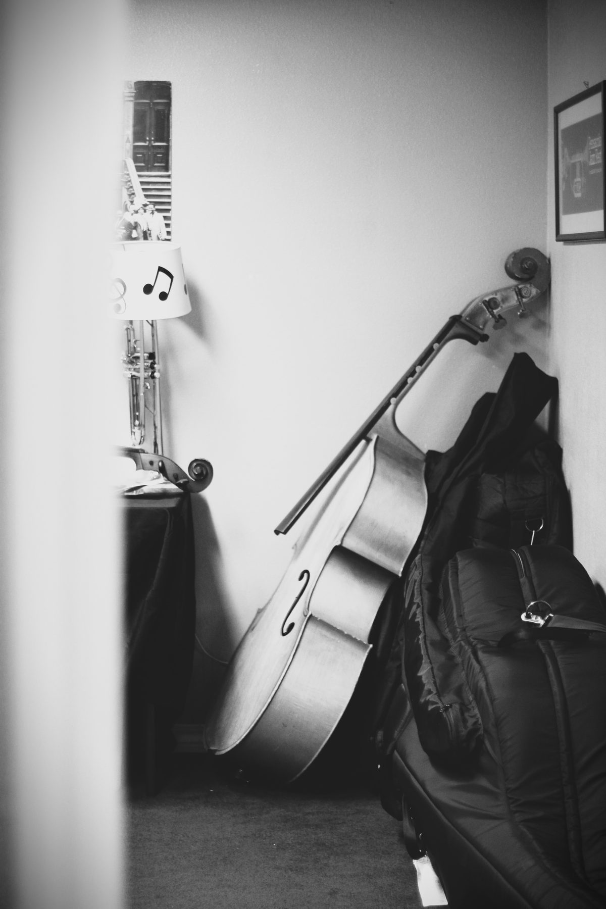 Black-and-white still of an upright bass resting in a hallway