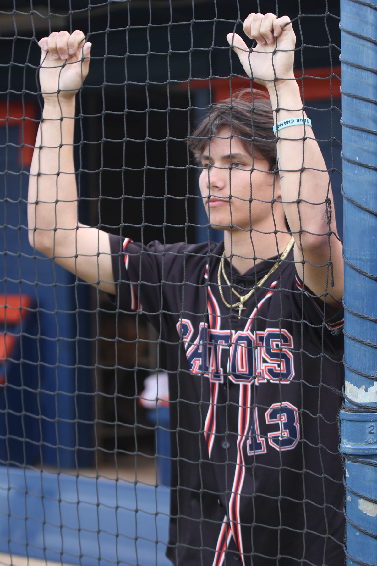 Baseball senior portrait gripping the backstop net in uniform