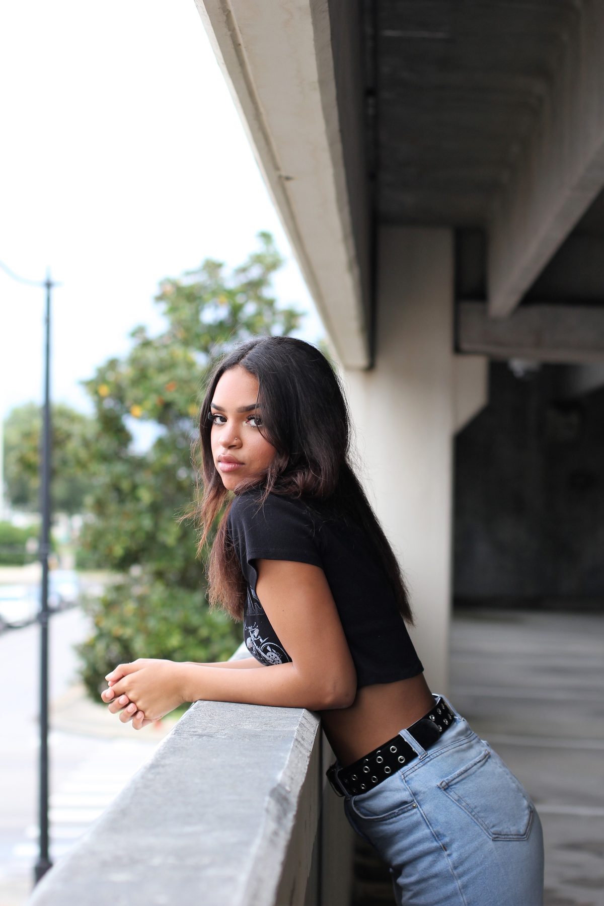 Portrait of a young woman leaning on a concrete balcony rail under an overpass