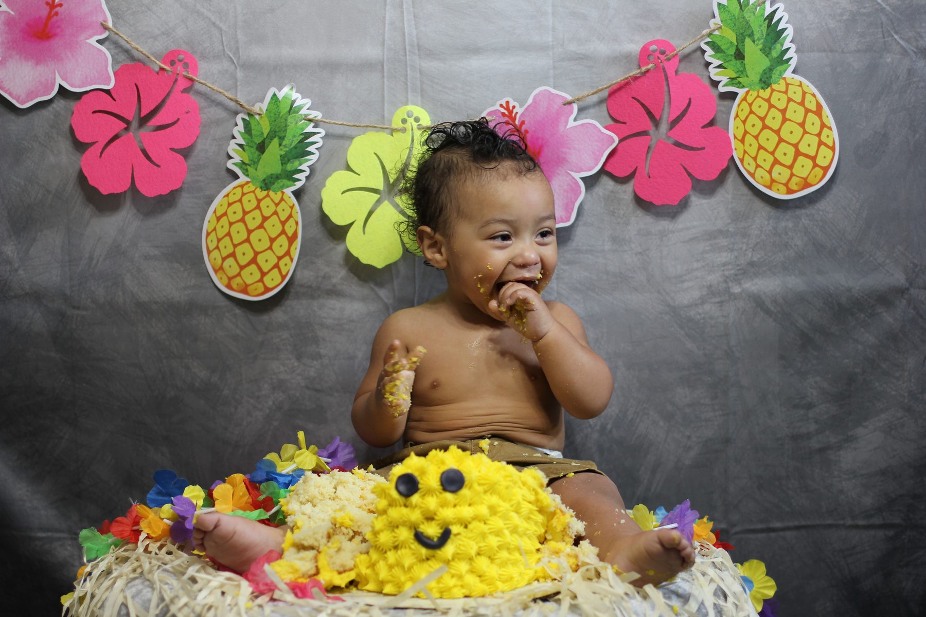 Baby's first-birthday cake smash with pineapple luau decorations
