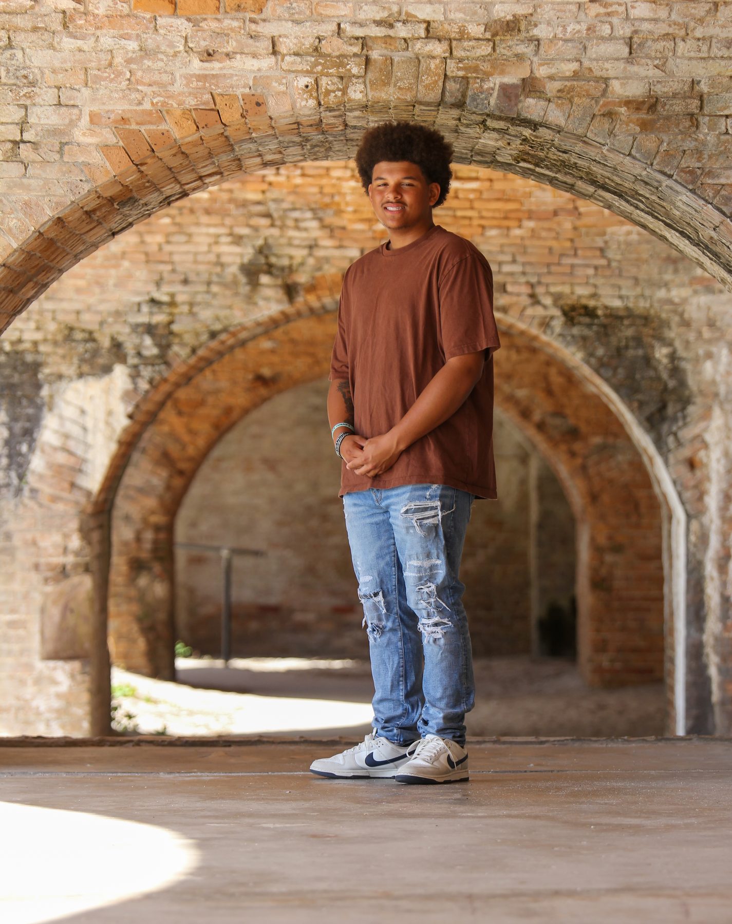 Senior portrait of a young man beneath the brick arches of a historic Pensacola fort
