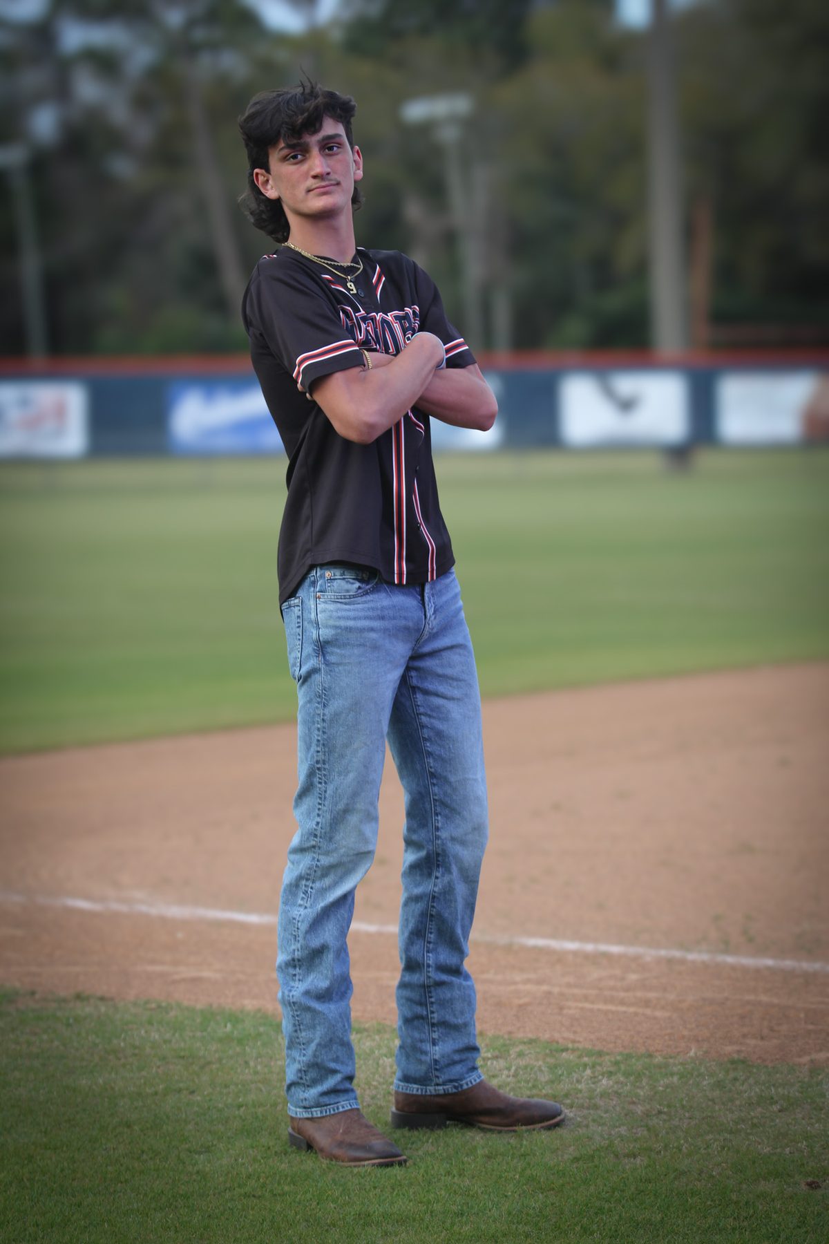 Senior portrait of a young man standing on the outfield of a baseball diamond