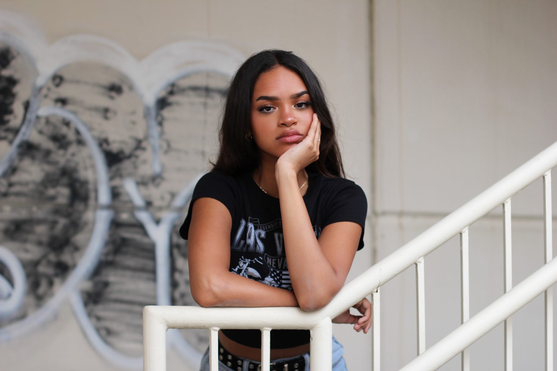 Editorial portrait on a white staircase against a graffiti-covered wall