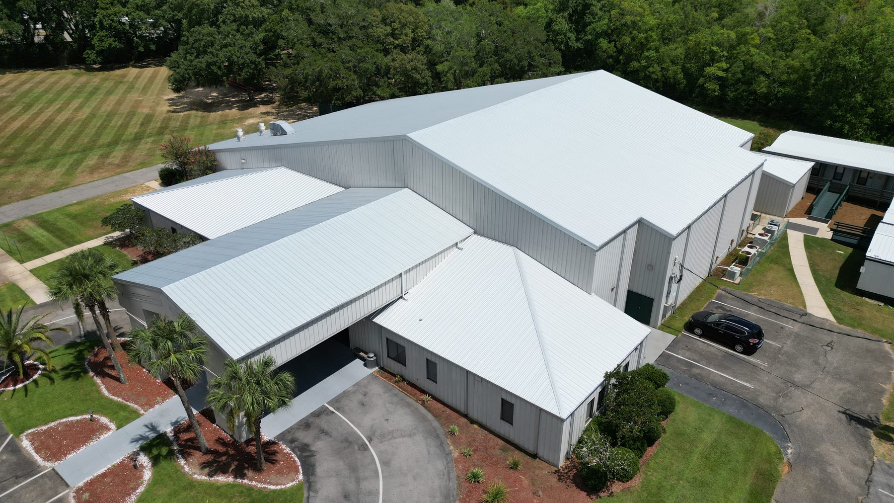 Aerial showcase of a commercial property with white metal roofing and landscaped grounds near Pensacola