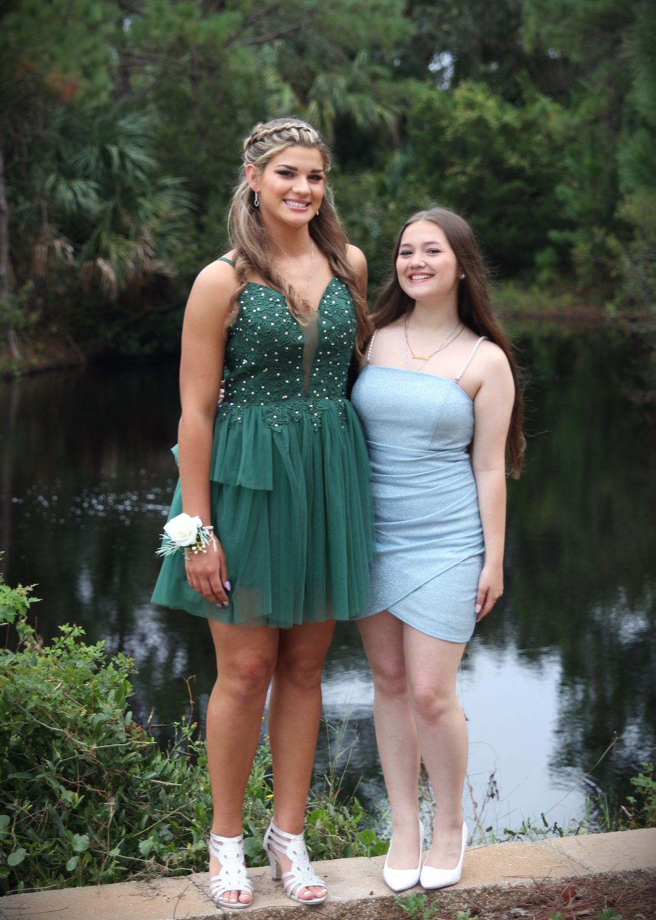 Two friends in prom dresses beside a shaded bayou
