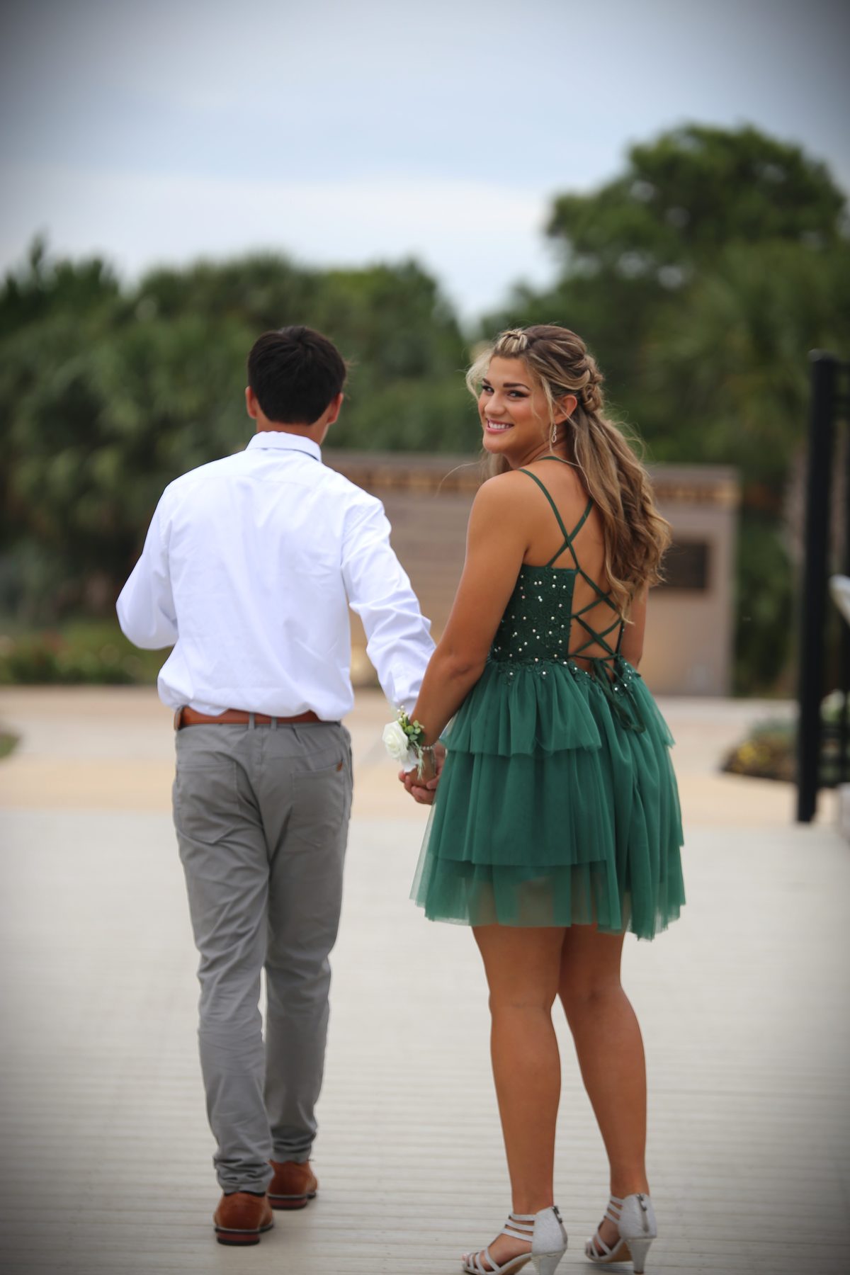 Prom couple walking hand in hand down a boardwalk