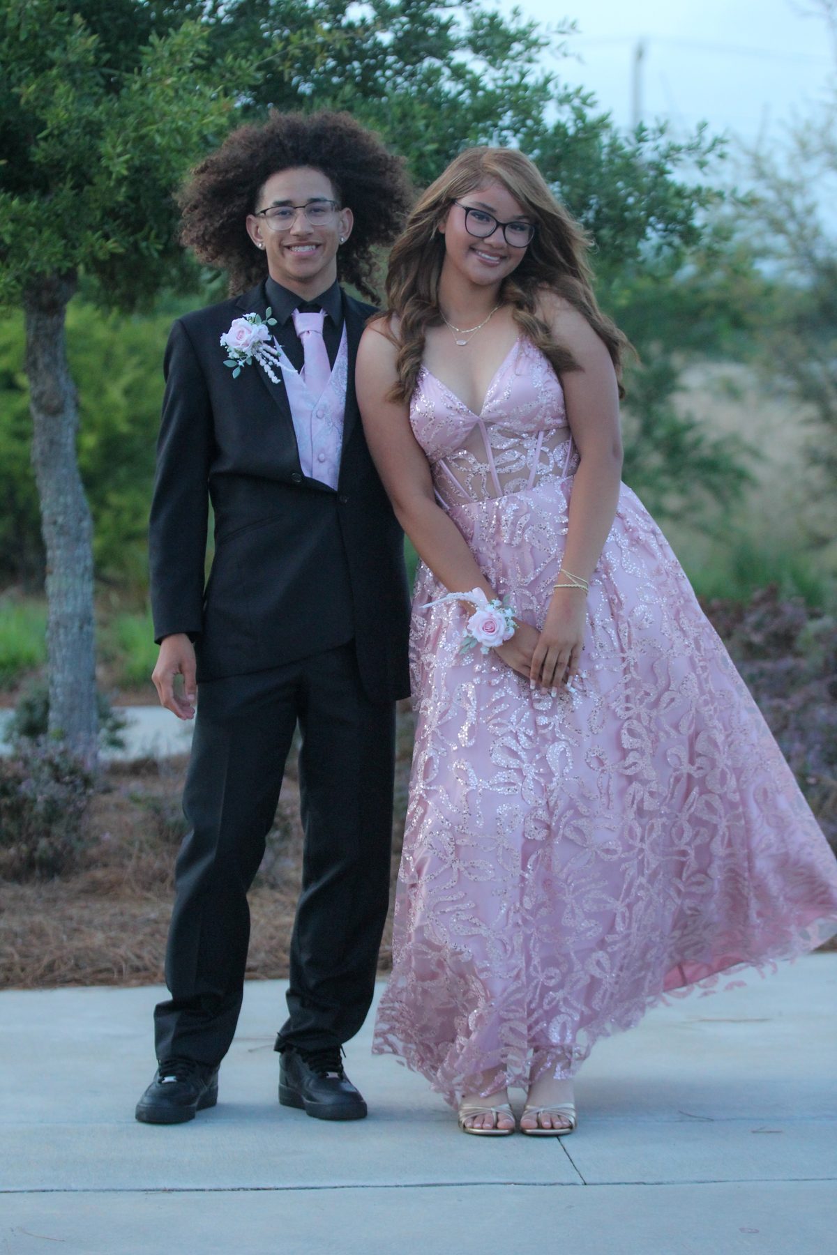 Prom couple laughing together beneath the trees