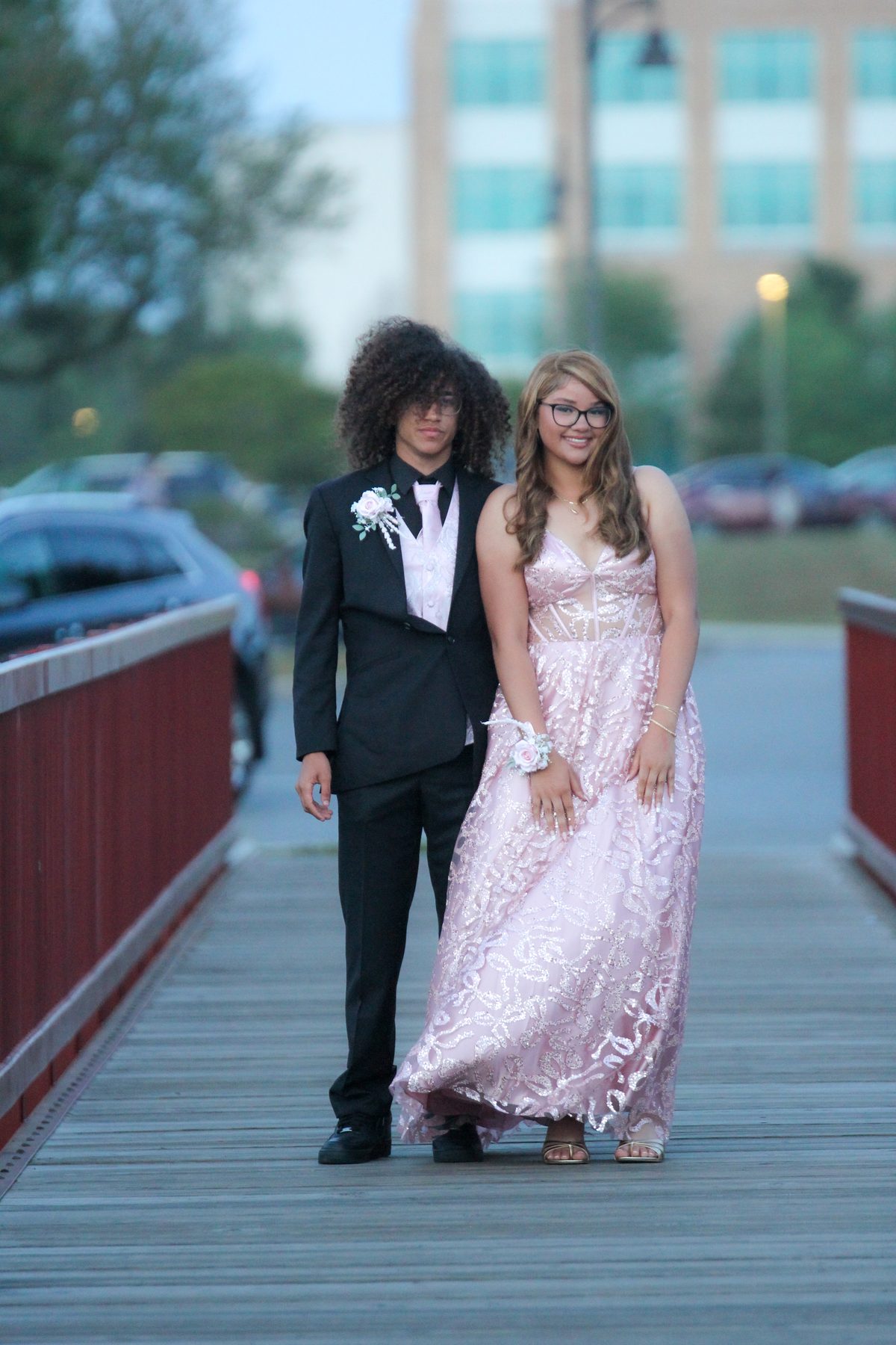 Prom couple posing on a red pedestrian bridge
