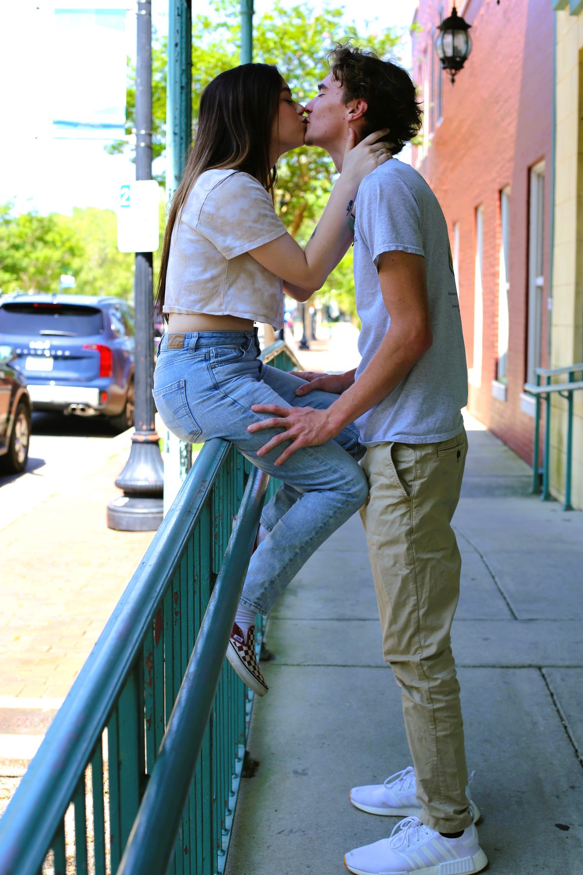 Couple stealing a kiss on a downtown Pensacola railing at golden hour