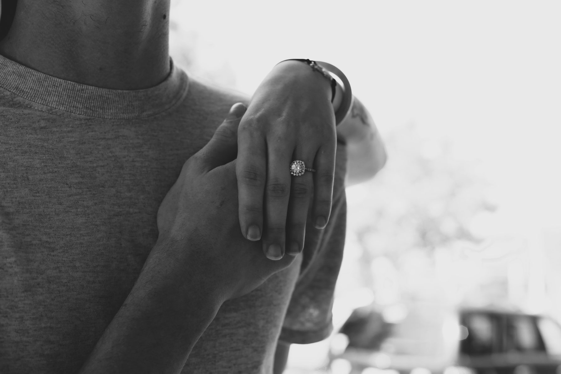 Black-and-white close-up of an engagement ring on clasped hands