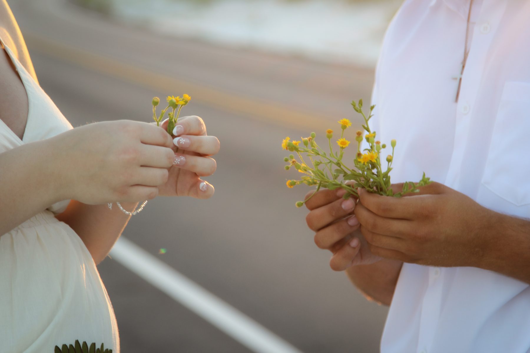 Close-up of a couple exchanging yellow wildflowers